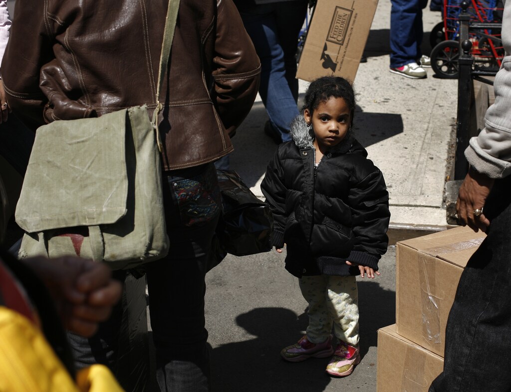 A child waits in line with her mother to receive goods from the Feed The Children relief organization