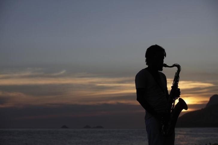 A musician plays saxophone at Arpoador beach as the sun sets in Rio de Janeiro February 12, 2010. REUTERS/Ricardo Moraes (BRAZIL - Tags: SOCIETY)