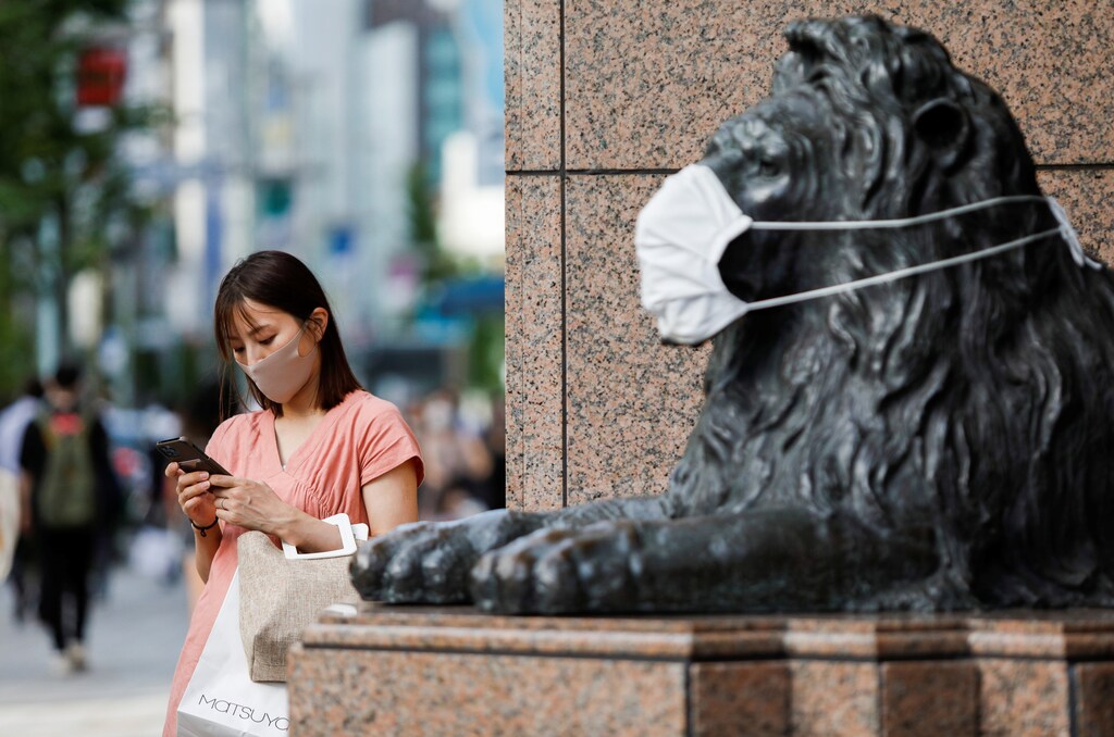 A woman wearing protective face mask stands next to a masked lion statue in Ginza shopping area, amid the coronavirus disease (COVID-19) outbreak in Tokyo, Japan August 5, 2021. REUTERS/AndronikiÂ Christodoulou - RC2VYO9IE4OT