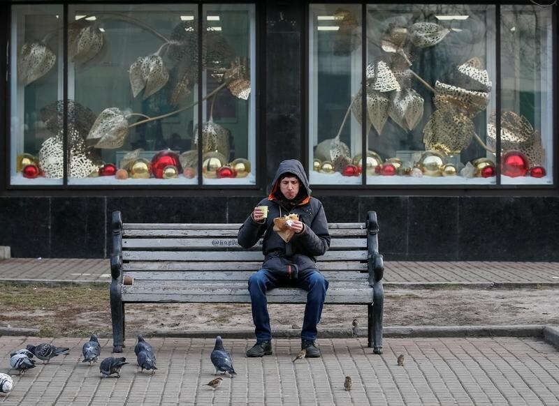 A man eats a sandwich and drinks a coffee as pigeons wait for the food in central Kiev, Ukraine January 27, 2020. REUTERS/Gleb Garanich - RC2EOE9H2EUY