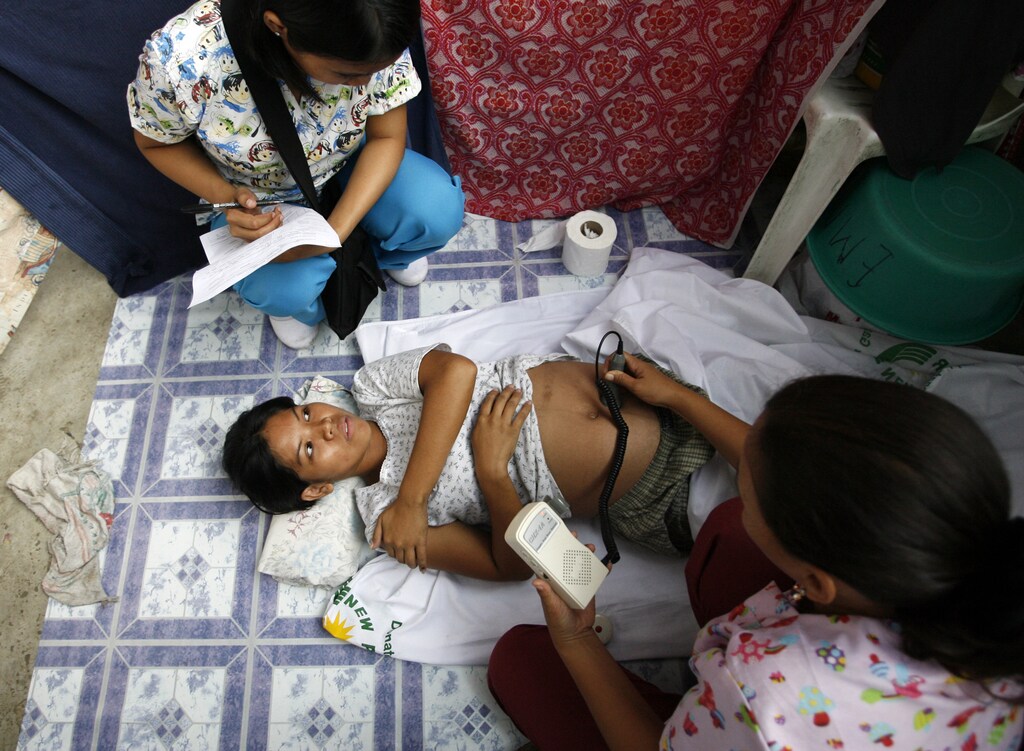 Midwives from the United Nations Population Fund (UNFPA) examine a pregnant woman at an evacuation centre in Laguna's San Pedro town, south of Manila November 4, 2009. Tens of thousands of people have been housed in evacuation centres for more than a month now after Typhoons Ketsana and Parma hit Metro-Manila and other towns in the Philippine island of Luzon