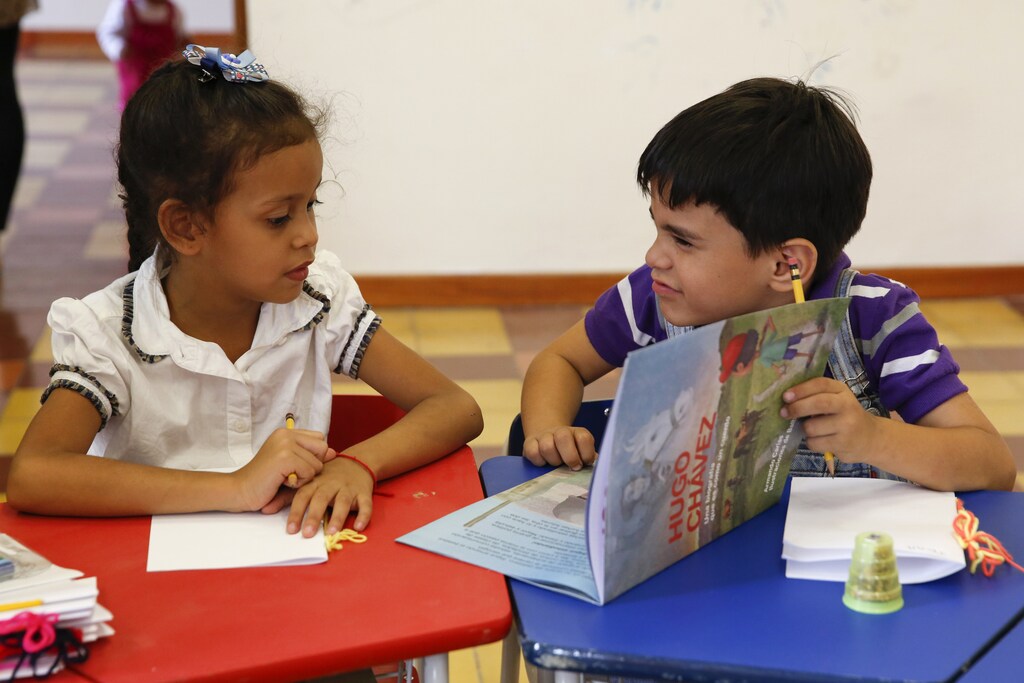 Children read a story book about the late Venezuelan President Hugo Chavez during a writing workshop at the 4F military fort in Caracas December 14, 2014. The Communication Ministry held the writing workshop for children last weekend to promote the legacy of the socialist leader who ruled Venezuela for 14 years until he died of cancer in 2013. Picture taken December 14, 2014. REUTERS/Carlos Garcia Rawlins (VENEZUELA - Tags: POLITICS SOCIETY) - GM1EACI049M01