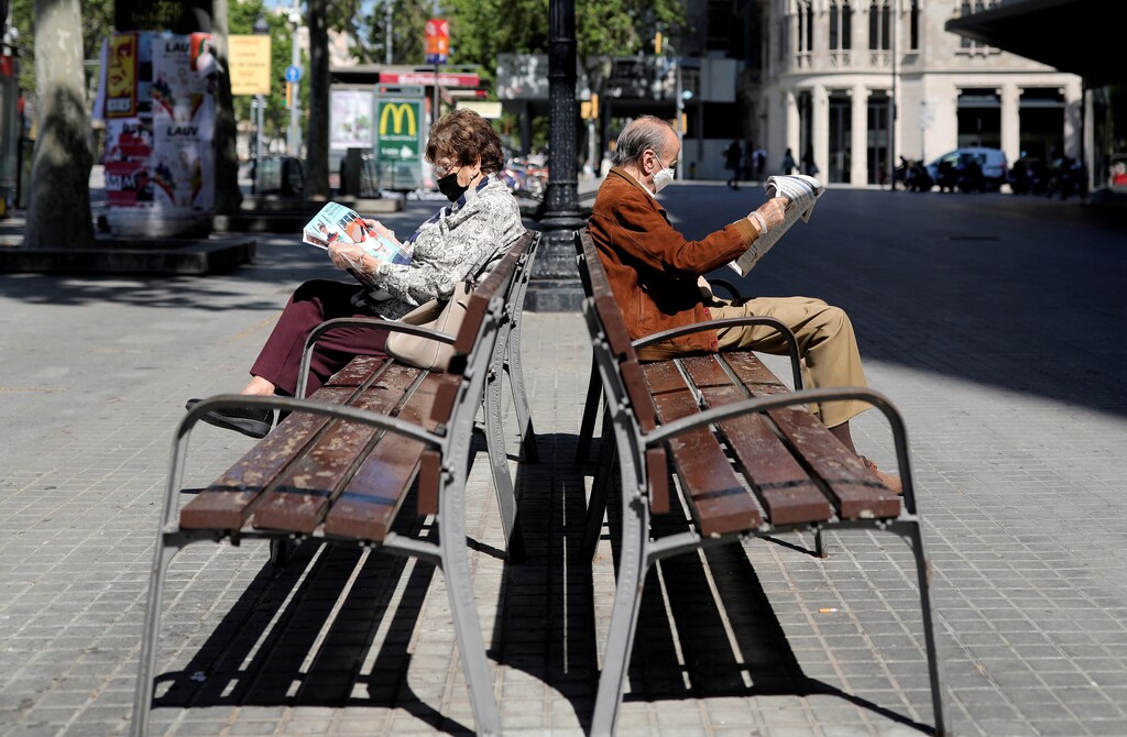 Elderly people wearing protective masks read newspapers as they sit on benches, during the hours in which the elderly are allowed to be outdoors, amid the coronavirus disease (COVID-19) outbreak, in Barcelona, Spain, May 4, 2020. REUTERS/Nacho Doce TPX IMAGES OF THE DAY - RC2OHG94T3AH