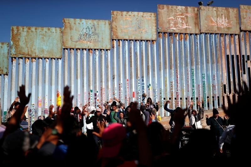 Migrants, part of a caravan of thousands trying to reach the U.S., pray by the border fence between Mexico and the United States, in Tijuana, Mexico November 15, 2018. REUTERS/Carlos Garcia Rawlins - RC19740C0490