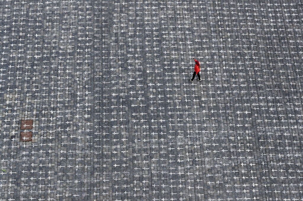 A woman walks across the Old Town Square where thousands of crosses have been painted on a pavement to commemorate the first anniversary since the death of the first Czech coronavirus disease (COVID-19) patient in Prague, Czech Republic, March 22, 2021. REUTERS/David W Cerny - RC2EGM9VM614