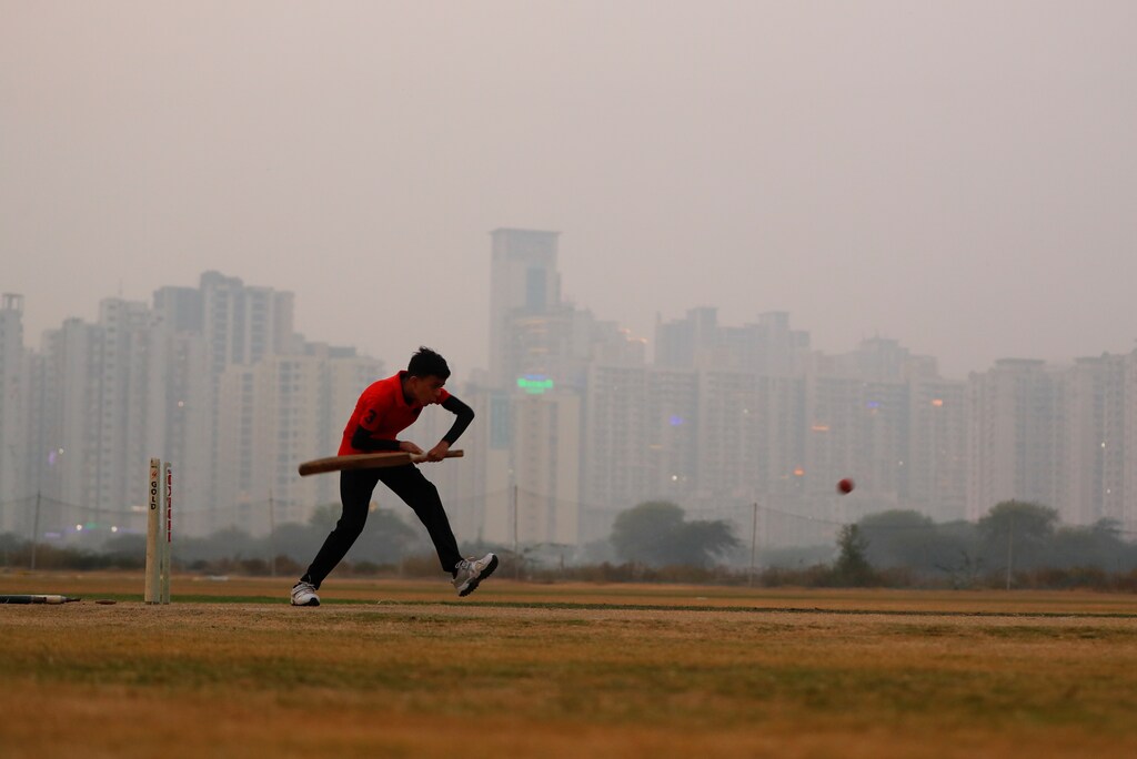 A boy plays cricket amidst smog at a playground in Noida on the outskirts of New Delhi, India, November 14, 2020.
