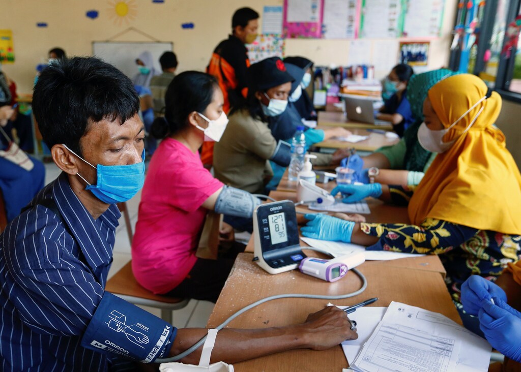 Patients in Jakarta, Indonesia, undergo health screening before being vaccinated for COVID-19.