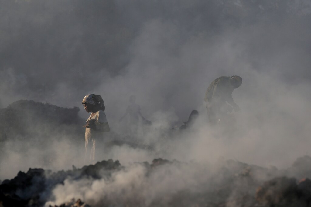 Locals walk among burning rubbish piles searching for items at the main garbage dump in Port-au-Prince, Haiti.