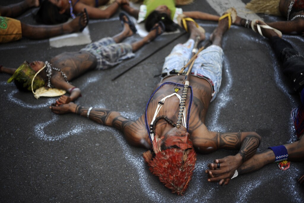 Munduruku Indians from the Amazon Basin demonstrate in front of the Ministry of Mines and Energy by lying on the street to symbolize the dead, in Brasilia June 11, 2013. The Indians are demonstrating against violations of indigenous rights and are calling for the suspension of the construction of the Belo Monte hydroelectric plant on the Xingu, Teles Pires and Tapajos rivers, a huge project aimed at feeding Brazil's fast-growing demand for electricity. REUTERS/Lunae Parracho (BRAZIL - Tags: ENVIRONMENT ENERGY CIVIL UNREST POLITICS SOCIETY)