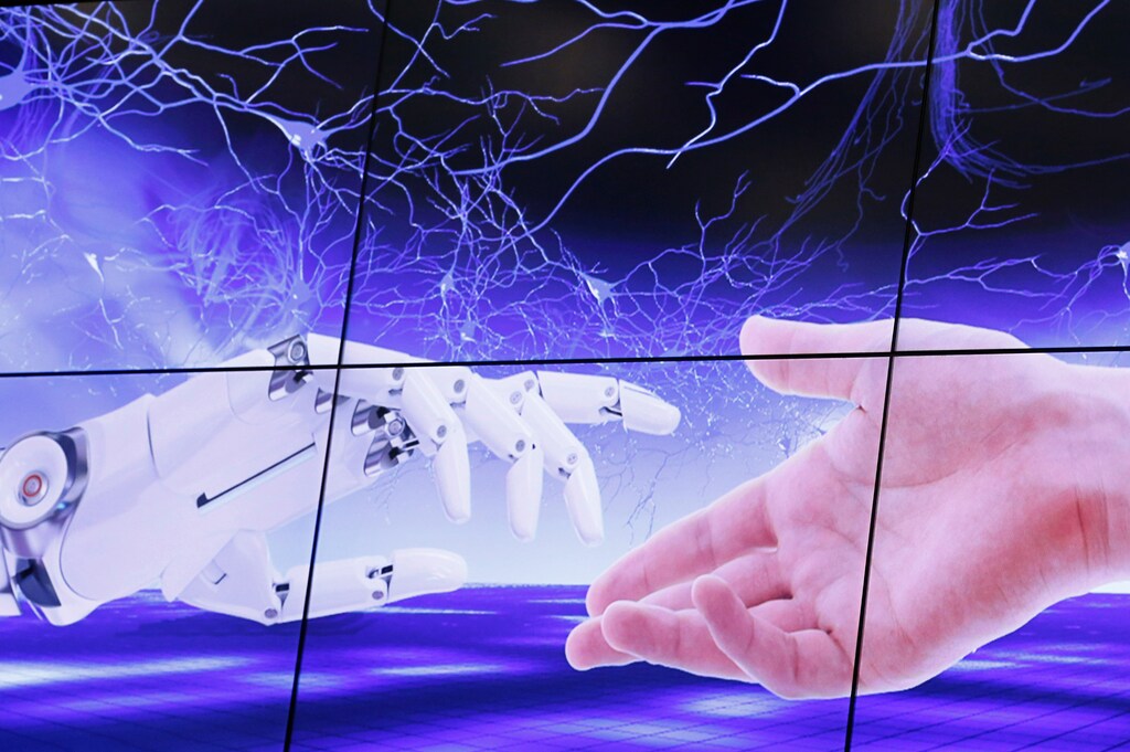 An illustration projected on a screen shows a robot hand and a human one moving towards each others during the "AI for Good" Global Summit at the International Telecommunication Union (ITU) in Geneva, Switzerland, June 7, 2017. REUTERS/Denis Balibouse - RC1248394150