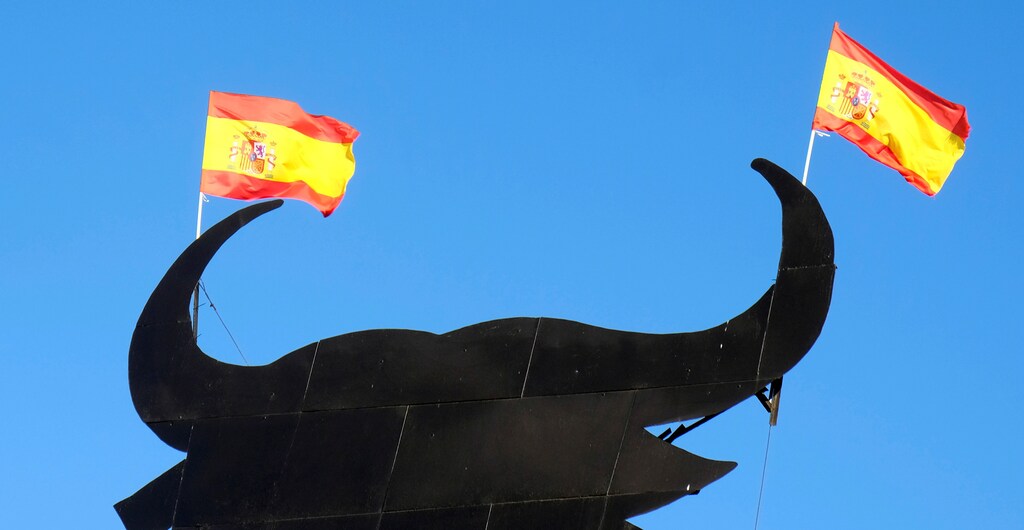 Spanish flags are attached to the horns of a billboard-size figure of a bull near Requena, Spain