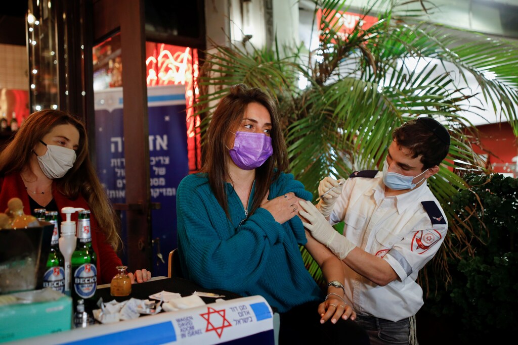 A woman receives a vaccination against the coronavirus disease (COVID-19) as part of a Tel Aviv municipality initiative offering a free drink at a bar to residents getting the shot, in Tel Aviv, Israel February 18, 2021. REUTERS/Corinna Kern - RC26VL9AZFSZ
