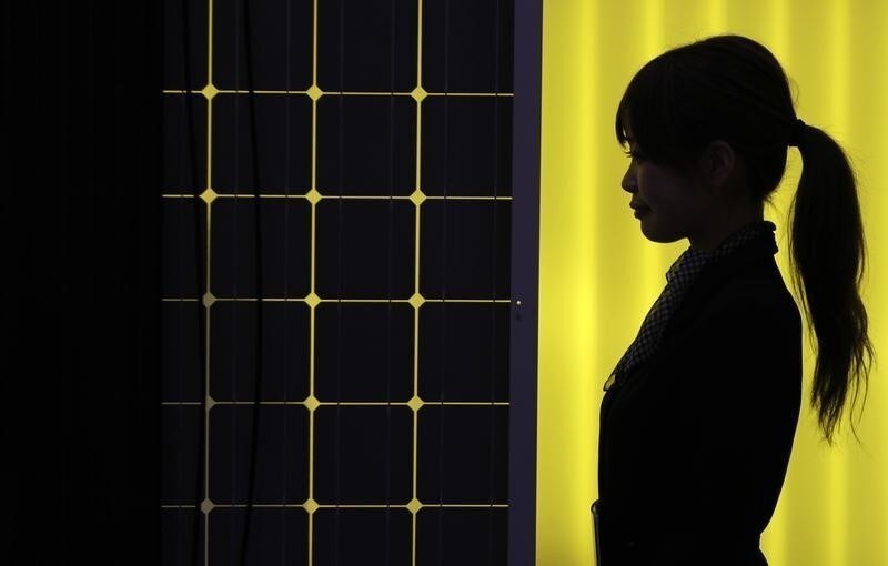 A woman is silhouetted next to a solar panel display by solar module supplier Upsolar at the fourth International Photovoltaic Power Generation (PV) Expo in Tokyo March 2, 2011. More than 600 companies in the solar energy business from 18 countries are taking part in the March 2-4 expo, which showcases firms and products related to photovoltaic power generation, according to the organiser. REUTERS/Yuriko Nakao (JAPAN - Tags: BUSINESS SCI TECH ENVIRONMENT) - RTR2JBUQ