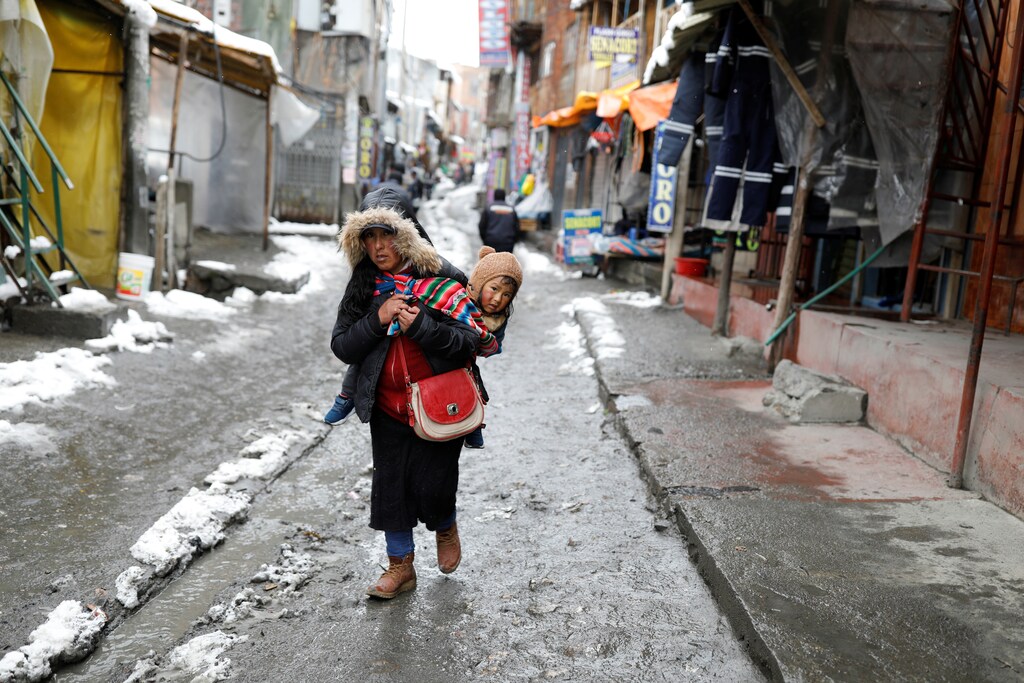 A woman carries a child as she walks down a street in La Rinconada, the Andes, Peru, October 4, 2019. REUTERS/Nacho Doce - RC2URF9NC2GA