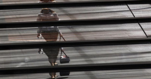 Image: An office worker is reflected on the roof of a building. REUTERS/Daniel Munoz