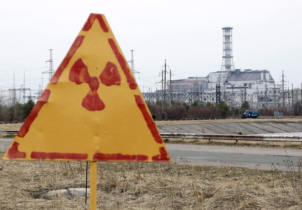 A radiation sign is seen, with a sarcophagus covering the damaged fourth reactor at the Chernobyl nuclear power plant in the background, April 4, 2011. Belarus, Ukraine and Russia will mark the 25th anniversary of the nuclear reactor explosion in Chernobyl, the place where the world's worst civil nuclear accident took place, on April 26. Engineers are still struggling to regain control of damaged reactors at the Fuskushima plant after last month's earthquake and tsunami, in the worst nuclear crisis since Chernobyl in 1986, with the government urging the operator of the plant to act faster to stop radiation spreading. REUTERS/Gleb Garanich (UKRAINE - Tags: ANNIVERSARY DISASTER ENERGY ENVIRONMENT) - RTR2KTBP