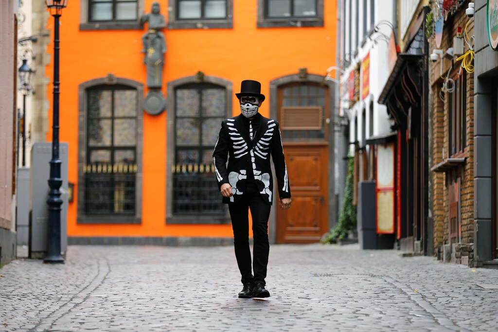 A lonely carnival reveller dressed as "The Death" walks through an empty street as the traditional celebrations for the start of the famous Cologne carnival season are officially cancelled due to the spread of the coronavirus disease (COVID-19) in Cologne, Germany, November 11, 2020. REUTERS/Thilo Schmuelgen - RC2Z0K9WZTZB