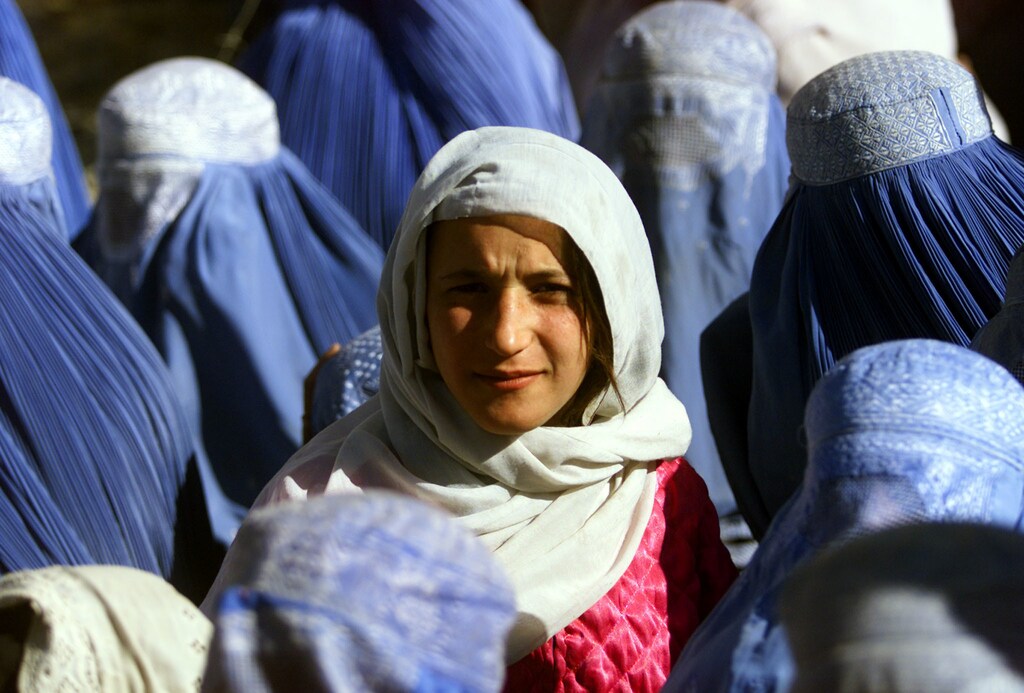 A young Afghan woman shows her face in public for the first time after5 years of Taliban Sharia law as she waits at a food distributioncentre in central Kabul November 14, 2001. Under its strictinterpretation of Islam, the Taliban ordered all women hidden behindhead-to-toe burqas. REUTERS/Yannis BehrakisAS - RP2DRIQQECAB