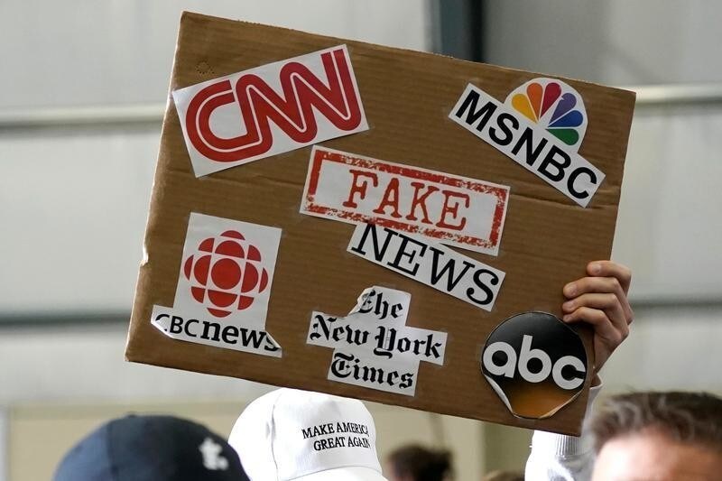 A sign showing major news organizations along with the words "fake news" is held up as U.S. President Donald Trump speaks at a Make America Great Again Rally in Washington, Michigan April 28, 2018.