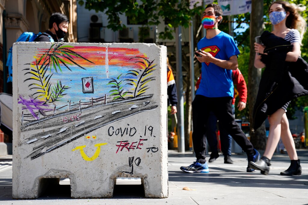 People in face masks walk past a 'COVID-19 Free' sign in Melbourne after coronavirus disease (COVID-19) restrictions were eased for the state of Victoria, Australia, October 28, 2020. REUTERS/Sandra Sanders - RC2CRJ9OQWHD