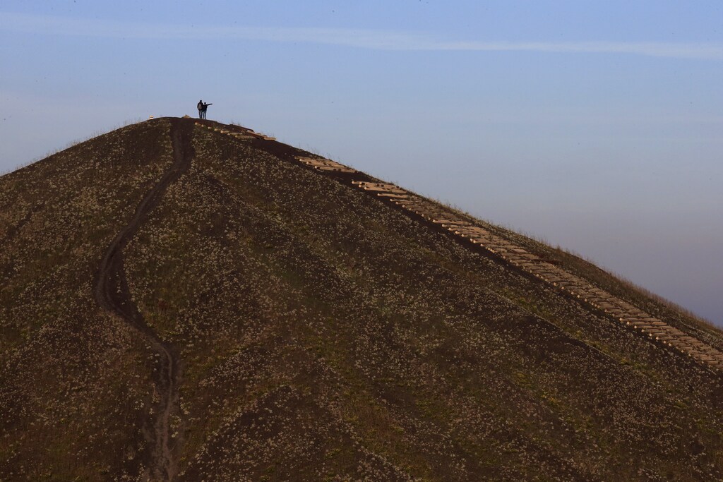 Net-zero transition: Two hikers stand at the top of one of the 11/19 pit and twin slag heaps at the former coal mine site in Loos-en-Gohelle, northern France, October 31, 2015. Loos-en-Gohelle, a town of 7000 inhabitants in the North of France, marked by the closure of coal mines in 1970, has demonstrated a successful transition from coal to a green economy. The city has joined the network of French positive energy territories, with almost 350 direct and indirect jobs created around the eco-activities and renewable energy in 10 years. On December 3, 2015, the Nord-Pas-de-Calais region will propose a visit of Loos-en-Gohelle as a symbol of a 'sustainable energy city'. This event will be part of the COP21, the World Climate Summit hosted by Paris from November 30 to December 11, 2015. Picture taken October 31, 2015. REUTERS/Pascal Rossignol