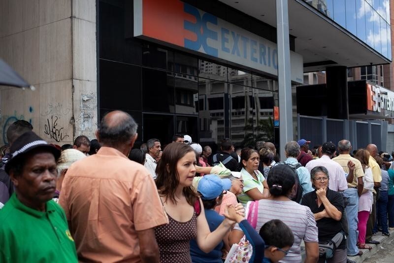People line up to withdraw cash from an automated teller machine (ATM) outside a Banco Exterior branch in Caracas, Venezuela August 16, 2018.