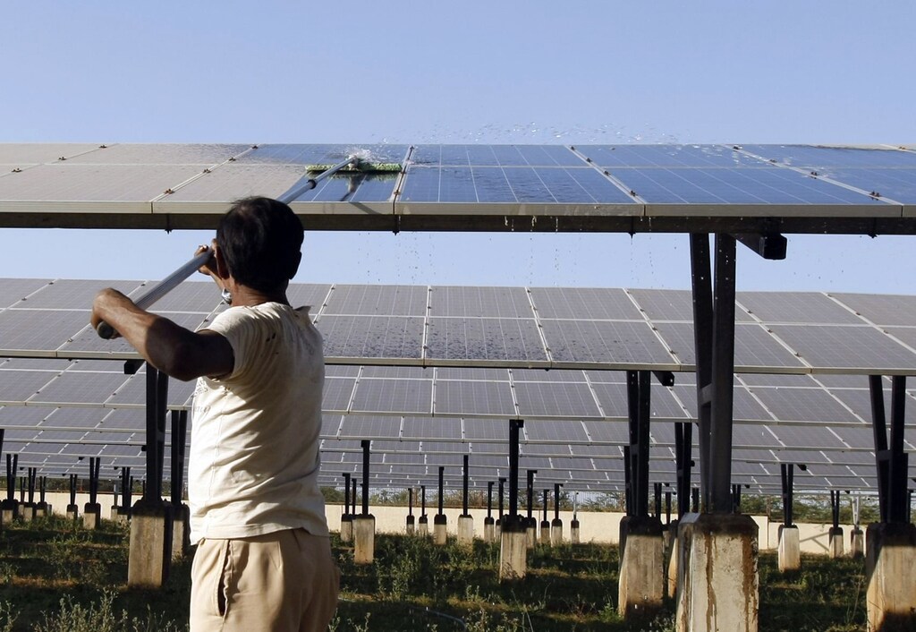 A worker cleans photovoltaic solar panels inside a solar power plant at Raisan village near Gandhinagar, in the western Indian state of Gujarat, February 11, 2014. India said on Tuesday it was investigating U.S. policies supporting solar panel makers, the latest move in an escalating row over renewable energy that has worsened already strained ties between the two countries. REUTERS/Amit Dave (INDIA - Tags: POLITICS BUSINESS ENERGY) - GM1EA2B1RYY01