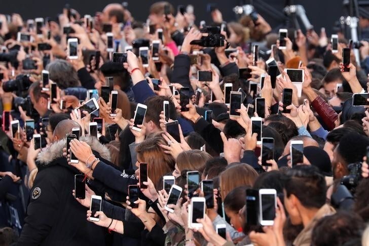 People use their smartphone to take photos of the L'Oreal fashion show on the Champs Elysees avenue during a public event organized by French cosmetics group L'Oreal as part of Paris Fashion Week, France, October 1, 2017. REUTERS/Charles Platiau