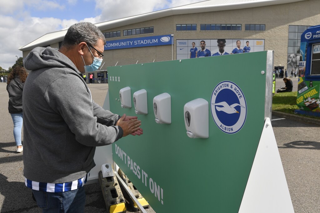 Soccer Football - Pre Season Friendly - Brighton & Hove Albion v Chelsea - The American Express Community Stadium, Brighton, Britain - August 29, 2020 A fan wearing a mask uses a hand sanitiser station outside the stadium before the match, as fans are allowed into a stadium following the outbreak of the coronavirus disease (COVID-19)