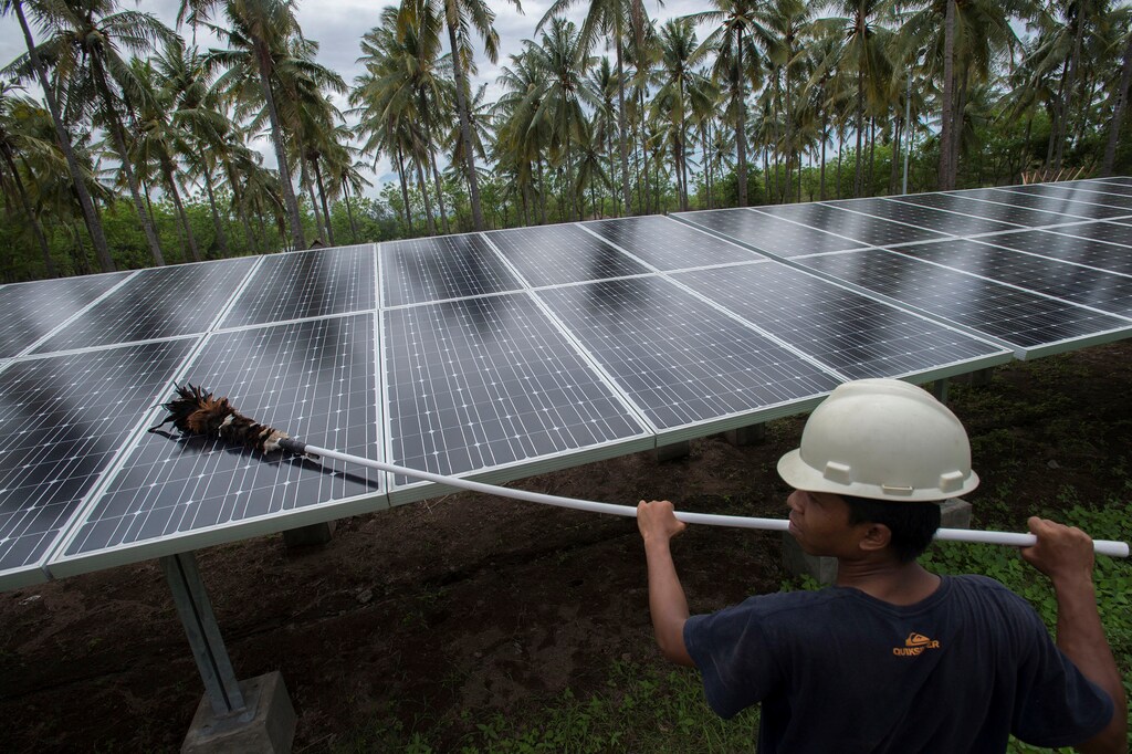 An employee of PT Perusahaan Listrik Negara (PLN) cleans the surface of solar panels at a solar power generation plant in Gili Meno island, in this December 9, 2014 photo taken by Antara Foto. REUTERS/Antara Foto/Widodo S. Jusuf./File Photo ATTENTION EDITORS - FOR EDITORIAL USE ONLY. THIS IMAGE HAS BEEN SUPPLIED BY A THIRD PARTY. MANDATORY CREDIT. INDONESIA OUT. - S1BEUKLBNJAA