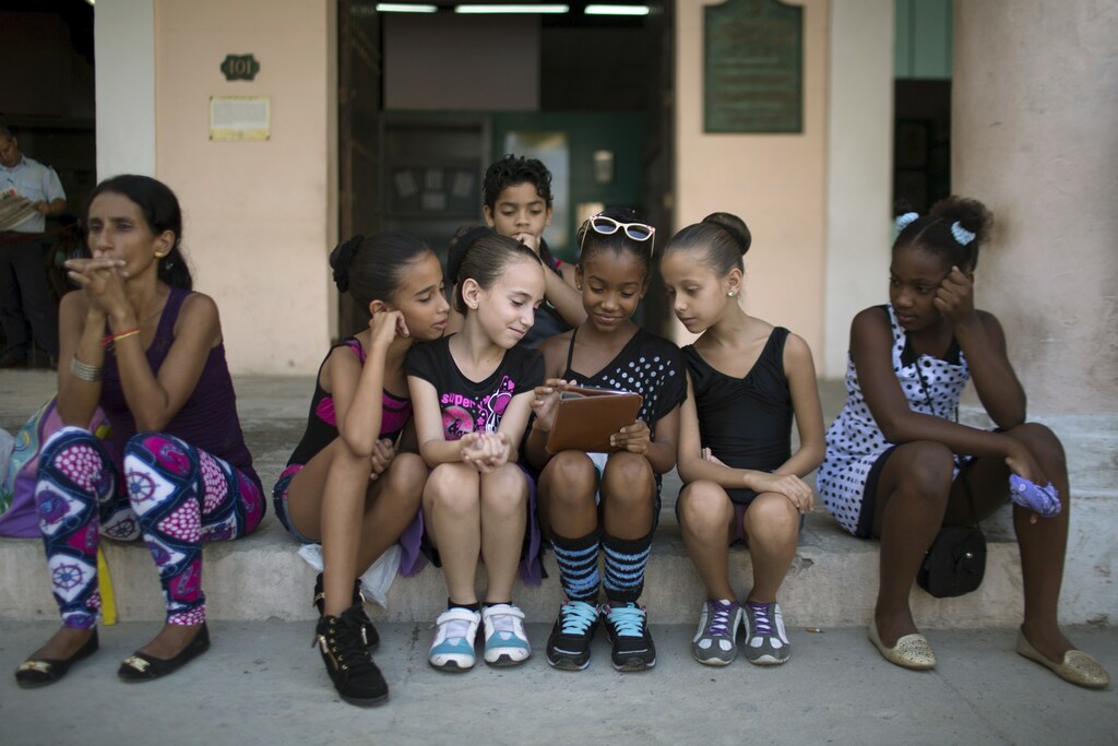 Children play with a tablet before performing at the first day of a contemporary urban dance festival in downtown Havana, April 15, 2015.