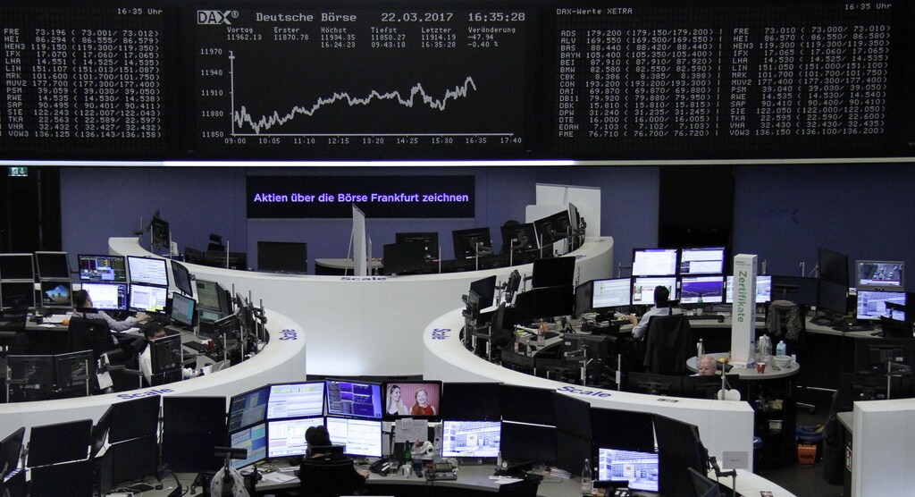 Traders work at their desks in front of the German share price index, DAX board, at the stock exchange in Frankfurt, Germany, March 22, 2017. REUTERS/Staff/Remote - RTX326S8