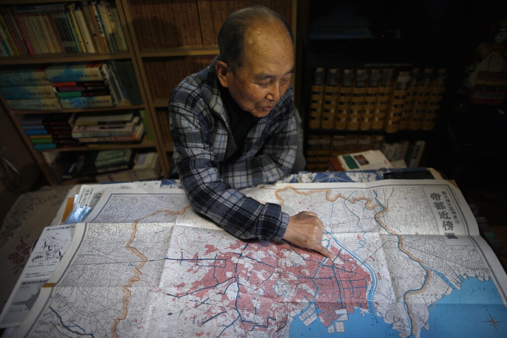 Japanese Katsumoto Saotome, 82, a survivor of Great Tokyo Air Raids in 1945, points to a map showing the burned central Tokyo areas in red after the bombing, during an interview with Reuters at his home in Tokyo March 4, 2015. Now, as memories fade of how civilians suffered during World War Two - suffering Saotome blames on Japan's wartime leaders who thought of their citizens as "weeds" - the author fears Japan may be marching towards war again. Picture taken March 4. REUTERS/Issei Kato (JAPAN - Tags: CONFLICT ANNIVERSARY POLITICS) - RTR4SJOQ