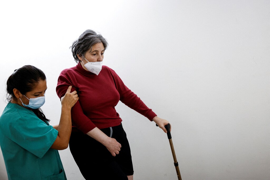 A stroke survivor walks with a cane and the help of neurological physiotherapist Guissela Rodriguez Palomino during treatment at Casaverde Neurological and Physical Rehabilitation Center in Navalcarnero, Spain.