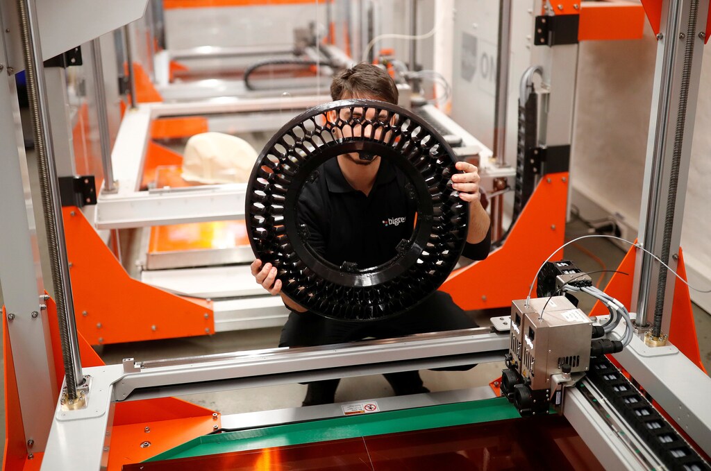 A designer checks a 3D-printed wheel of a motorcycle.