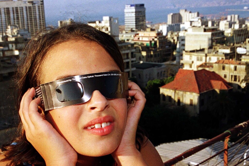 Ten-year-old Dima tries out for size a pair of solar eclipse glasses on the balcony of her Beirut apartment overlooking the Mediterranean during sunset August 10. Dima is one of thousands of Lebanese students who will have the day off school on Wednesday when the eclipse is expected to cover 87 percent of the sun when viewed in Lebanon. The government has deaclared Wednesday a school holiday and advised citizens to stay indoor drawing critisism it was scaring people instead of encouraging them to watch safely the eclipse.JS/JDP - RTRQR4G