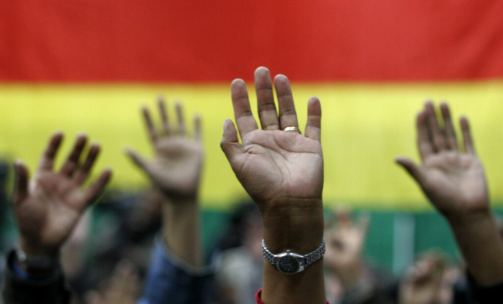 Members of Bolivia's Constituent Assembly raise their hands to vote during a session in Oruro, some 210 km (130 miles) south of La Paz, December 9, 2007.The assembly rewriting Bolivia's basic law reconvened on Saturday night to vote article by article on a draft constitution that has caused a deep split and violent protests in the poor Andean country. REUTERS/David Mercado (BOLIVIA) - RTX4K6X