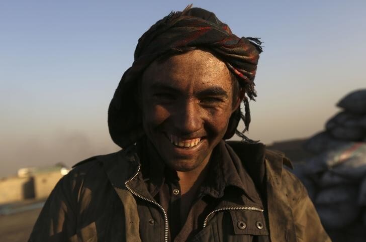 A labourer smiles as he takes a break from shoving coal at a coal dump site outside Kabul December 4, 2012. REUTERS/Omar Sobhani (AFGHANISTAN - Tags: SOCIETY BUSINESS EMPLOYMENT)