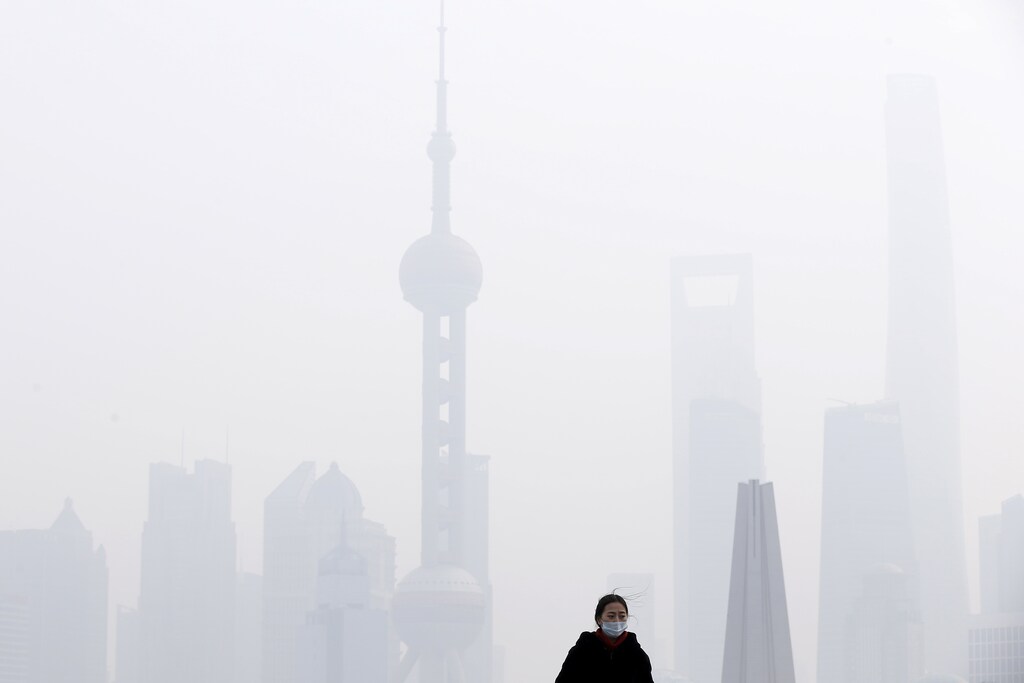 A woman wearing a face mask is seen in front of the financial district of Pudong amid heavy smog in Shanghai, China