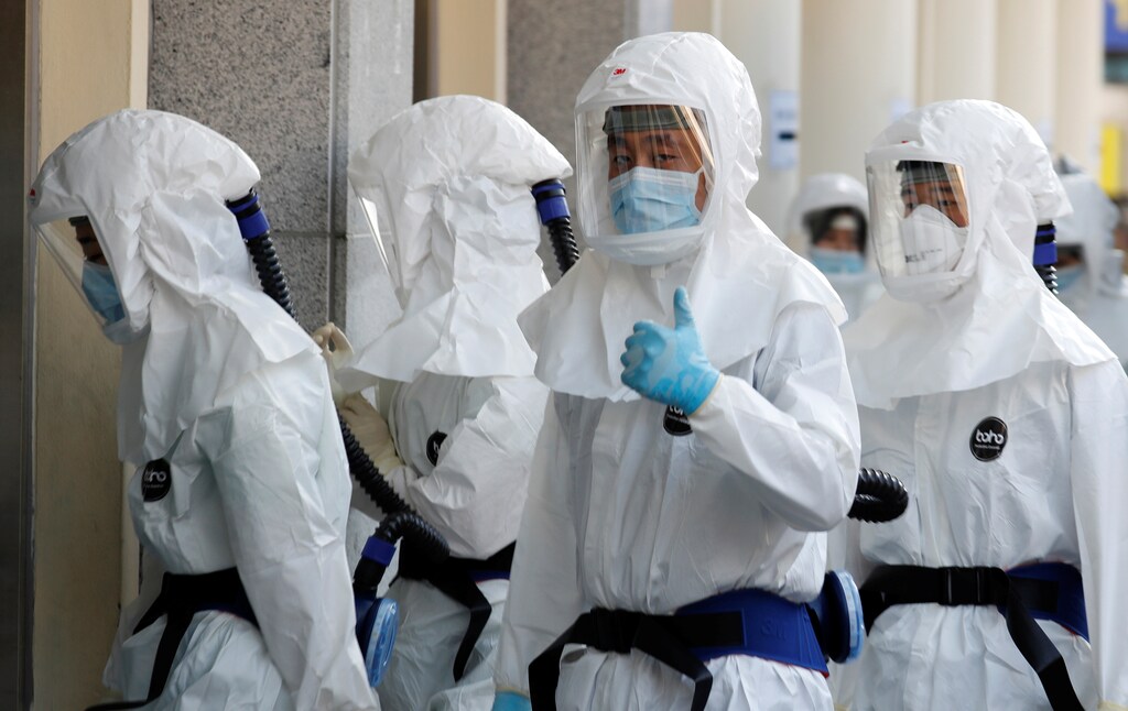 A medical worker in a protective gear thumbs up to media as he walks into a hospital facility to treat coronavirus patients amid the rise in confirmed cases of coronavirus disease (COVID-19) in Daegu, South Korea, March 8, 2020. REUTERS/Kim Kyung-Hoon - RC2KFF968JAE