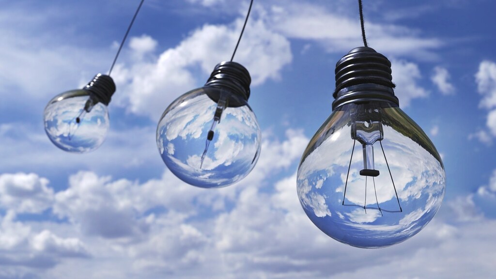 Three transparent light bulbs against a blue sky