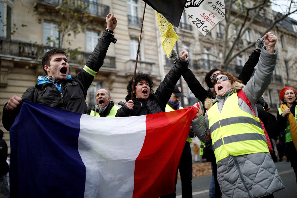 Protestors wearing yellow vests hold a French flag during a demonstration against French government's pensions reform plans in Paris as part of a second day of national strike and protests in France, December 10, 2019. REUTERS/Benoit Tessier - RC2DSD9VOPFP