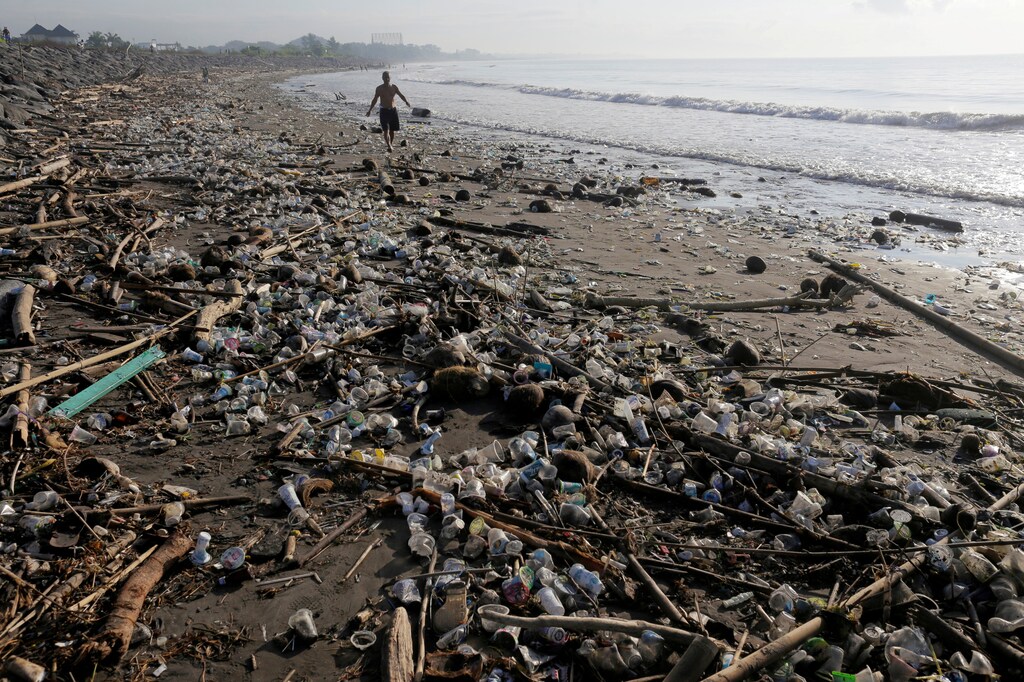 A local resident walks along a section of Matahari Terbit beach covered in plastic and other debris washed ashore by seasonal winds near Sanur, Bali, Indonesia April 11, 2018. REUTERS/Johannes P. Christo TPX IMAGES OF THE DAY - RC1AF6081DA0