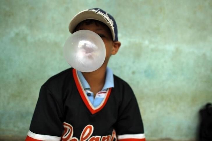 A child blows a bubble gum as he attends a donation of baseball equipments organized by Homerun hopefuls in Santo Domingo July 12, 2011. Homerun hopefuls is an American non-profit organization that collects both new and slightly used baseball equipment for impoverished children in the Dominican Republic. REUTERS/Eduardo Munoz (DOMINICAN REPUBLIC - Tags: SPORT BASEBALL SOCIETY FOOD)