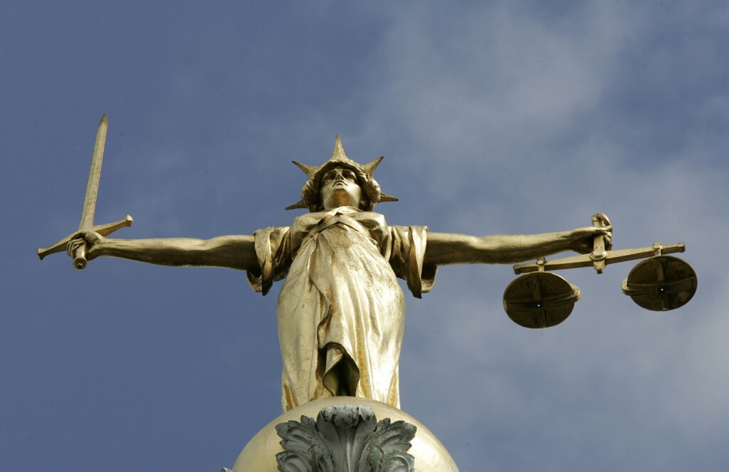 The Statue of Justice, depicted as a women with a sword in one hand and scale in her other, is seen on top of the London Central Criminal Court, the Old Bailey in London August 12, 2005. Britain may reform laws to ensure efforts to deport foreign nationals deemed a threat to national security, are not blocked by judges over human rights concerns. - PBEAHUNXWFA