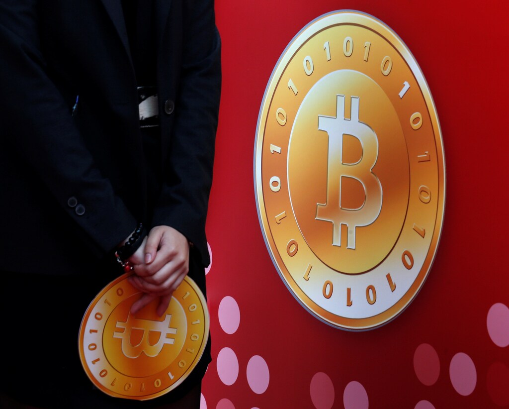 An attendant holds a bitcoin sign during the opening of Hong Kong's first bitcoin retail store February 28, 2014. REUTERS/Bobby Yip/File Photo - RTSKSMZ