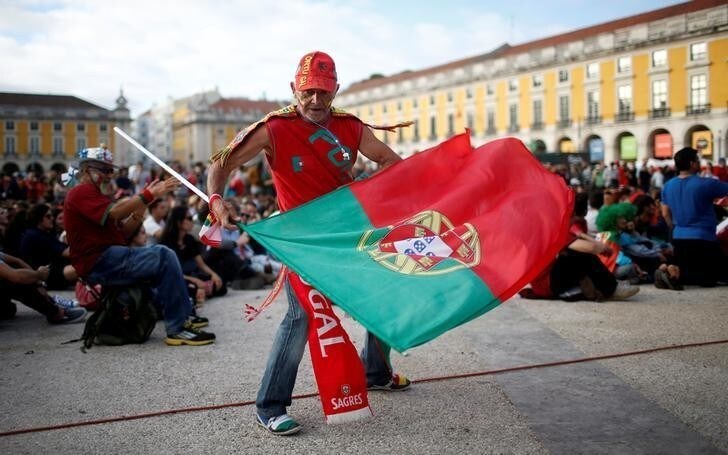 A fan of Portugal dances with a flag before the Euro 2016 match between Portugal and Iceland at a public screening in downtown Lisbon, Portugal, June 14, 2016.