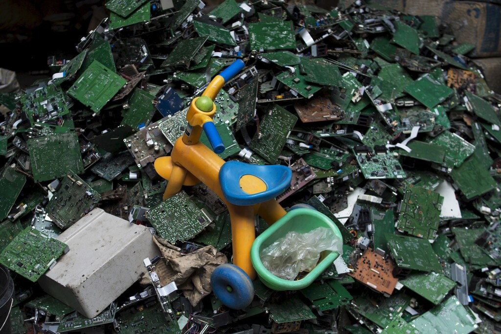 A toy tricycle is seen on circuit boards at a workshop in the township of Guiyu in China's southern Guangdong province June 8, 2015. REUTERS/Tyrone Siu