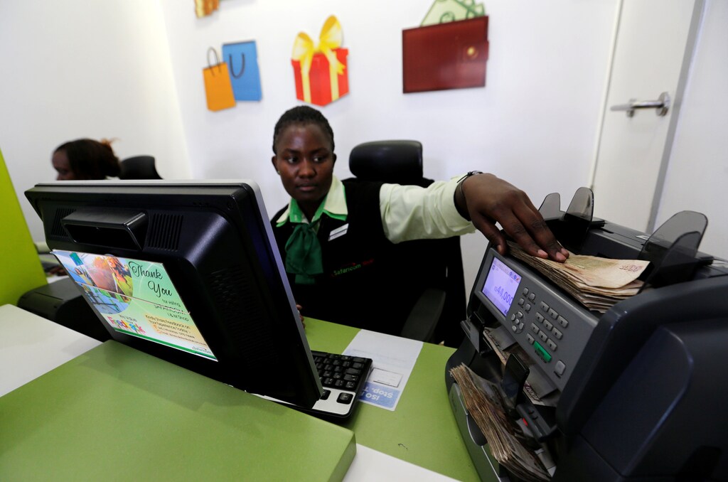 An employee uses a money-counting machine as she serves a customer inside a mobile-phone care centre in Nairobi.