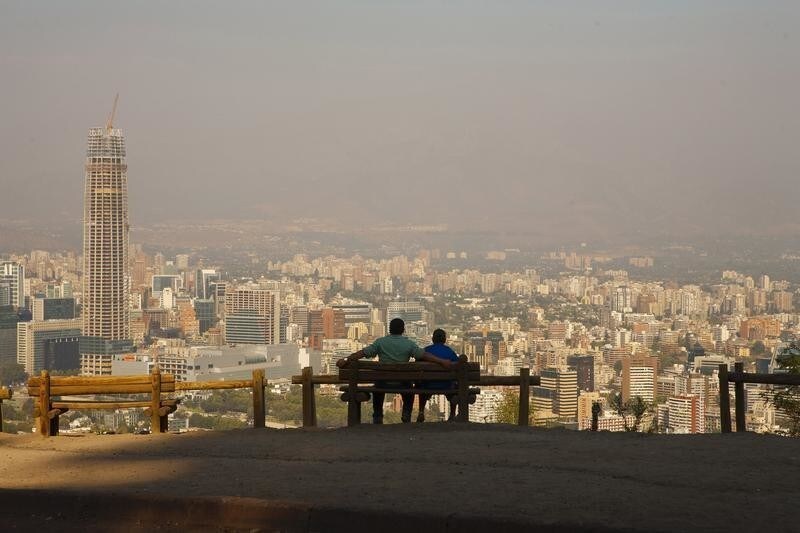 A man (L) sits with his son while enjoying the view of the Andes Mountains Range at the San Cristobal Hill in Santiago de Chile February 8, 2012. The Chilean capital city is covered with smoke coming from a forest fire near the southern zone of Pichilemu, about 200 km (124 miles) from Santiago. REUTERS/Minh Nguyen (CHILE - Tags: CITYSPACE SOCIETY ENVIRONMENT) - RTR2XIND